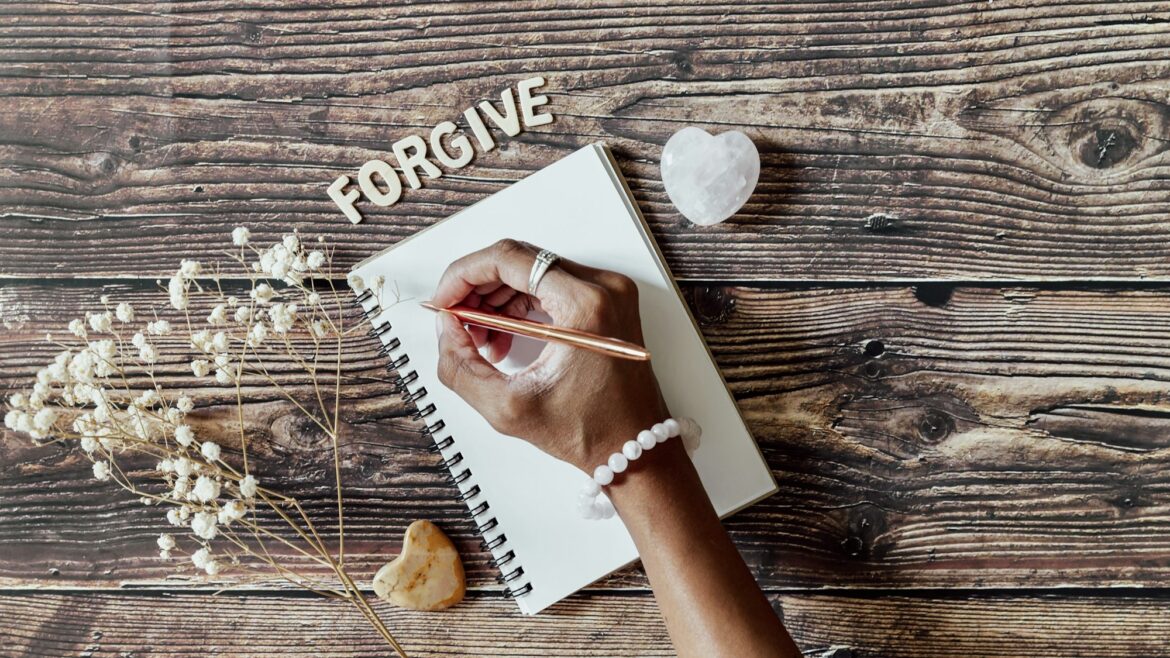 Hand writing a forgiveness list on a wooden table